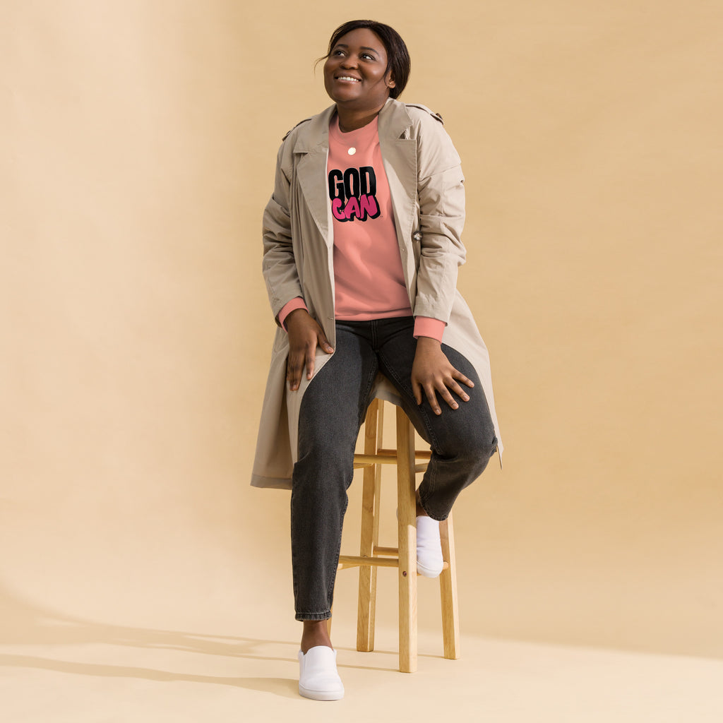 unisex-premium-sweatshirt-dusty-rose-front-model sitting on a stool with God Can text on front